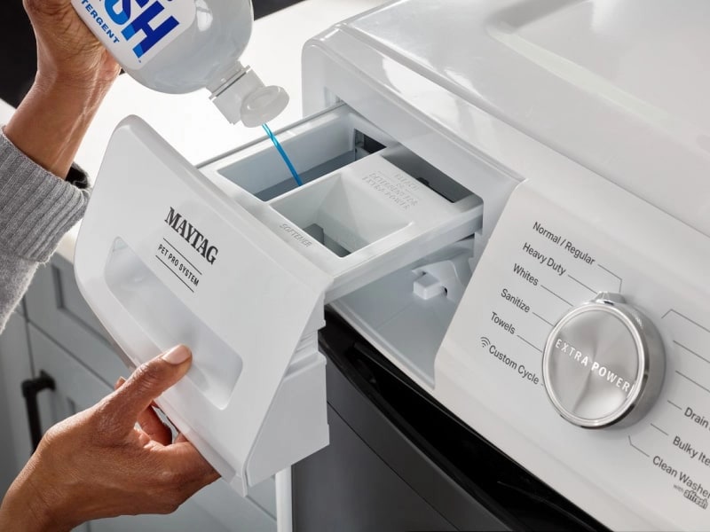 Person adding laundry detergent into a Maytag® Front Load Washer for pets