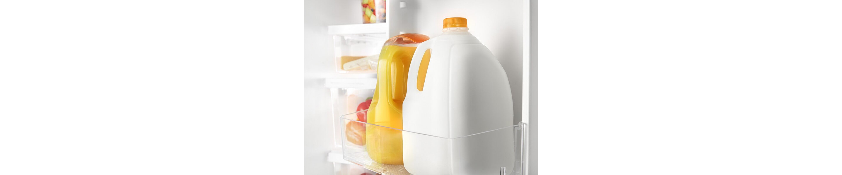 Milk and orange juice bottles in a refrigerator door shelf