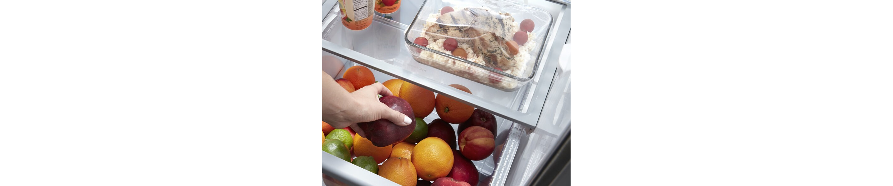 Person placing an apple inside a refrigerator drawer