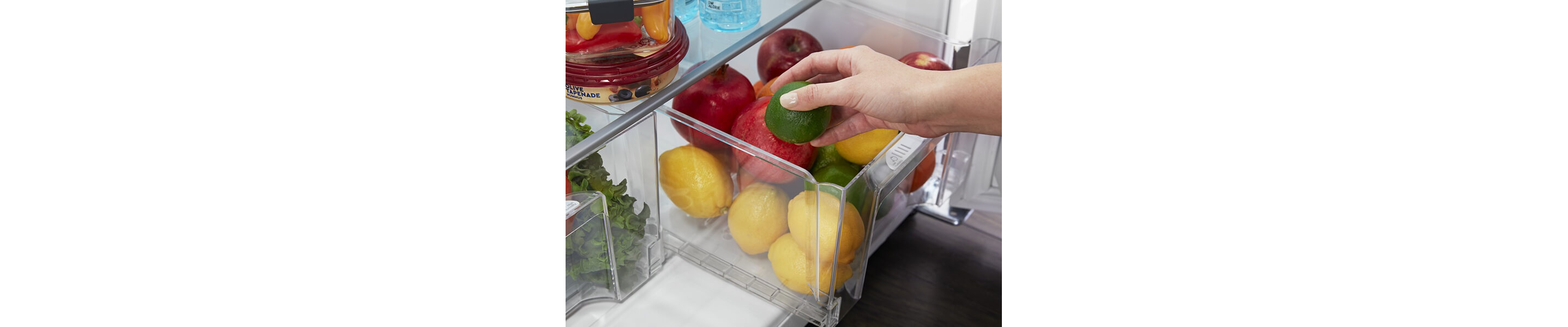 Person placing a lime inside a refrigerator drawer
