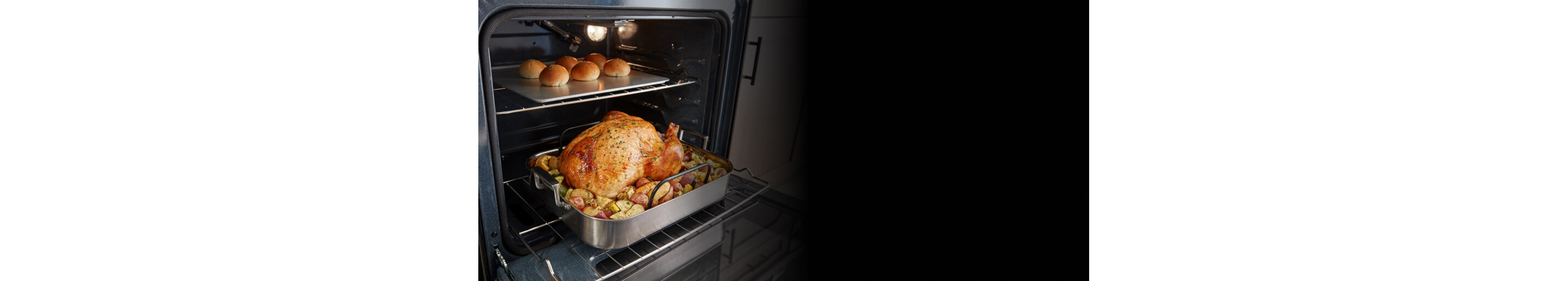 Whole chicken and rolls inside an oven