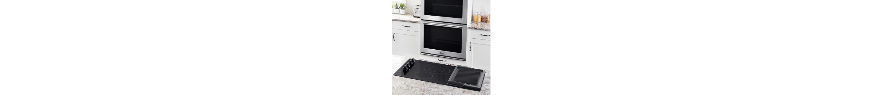 An induction cooktop with a double wall oven in the background