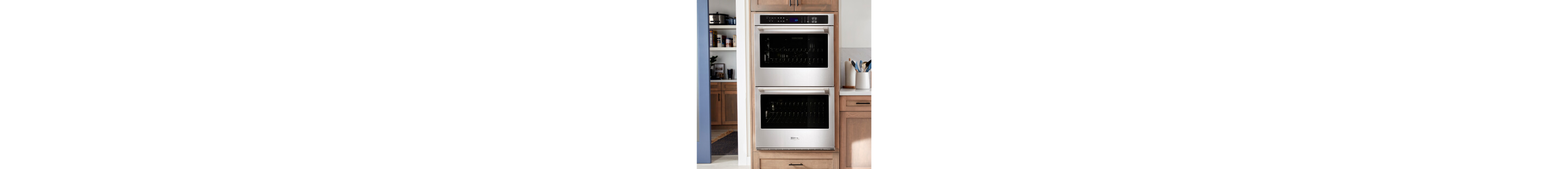 A double wall oven surrounded by brown cabinetry