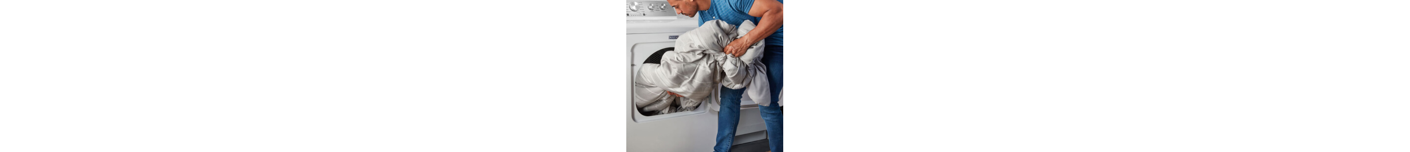 A person removing a comforter from a dryer