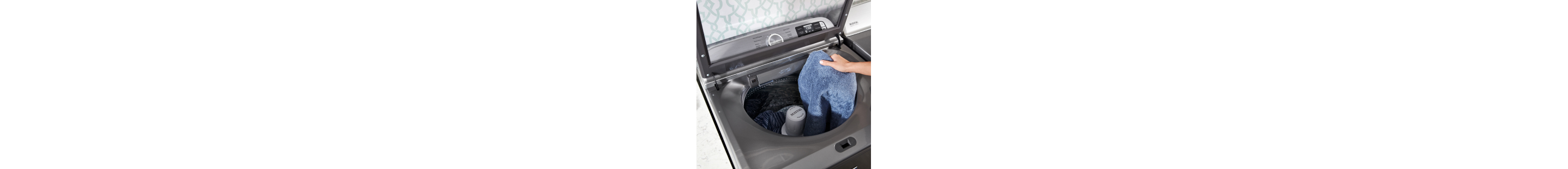 A person placing clothes into a washing machine