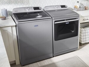 Maytag® top load washer and dryer in between cream cabinetry in a laundry room