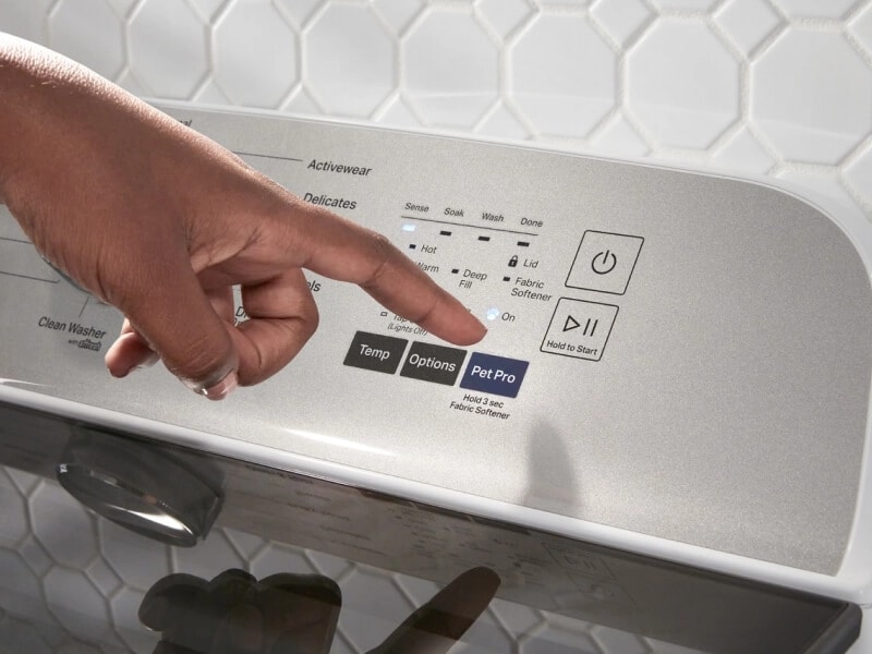 A hand pointing at the Pet Pro Option button on a Maytag® washer