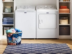 A basket of laundry next to a Maytag® top-load washer and dryer set 