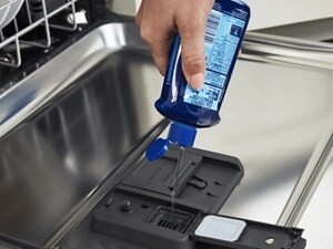 Person adding dishwasher detergent to a detergent dispenser