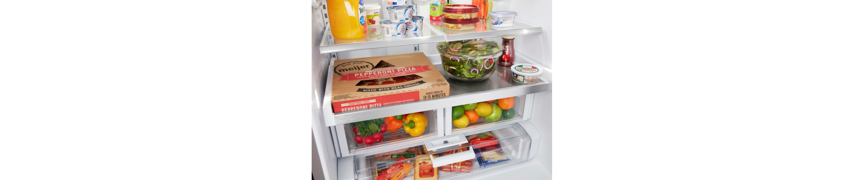 Open refrigerator with a view of full drawers with citrus and vegetables inside