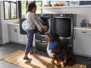 A pet owner pulling a dog bed out of an open front load washer