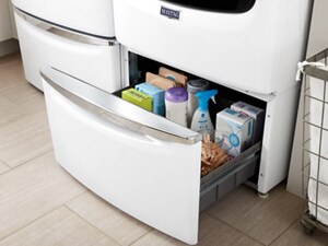 Storage drawer under the washing machine open to show contents