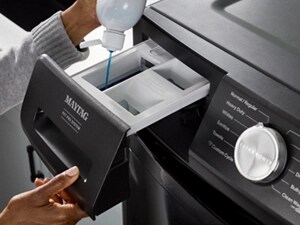 A person pouring detergent into a Maytag® washer