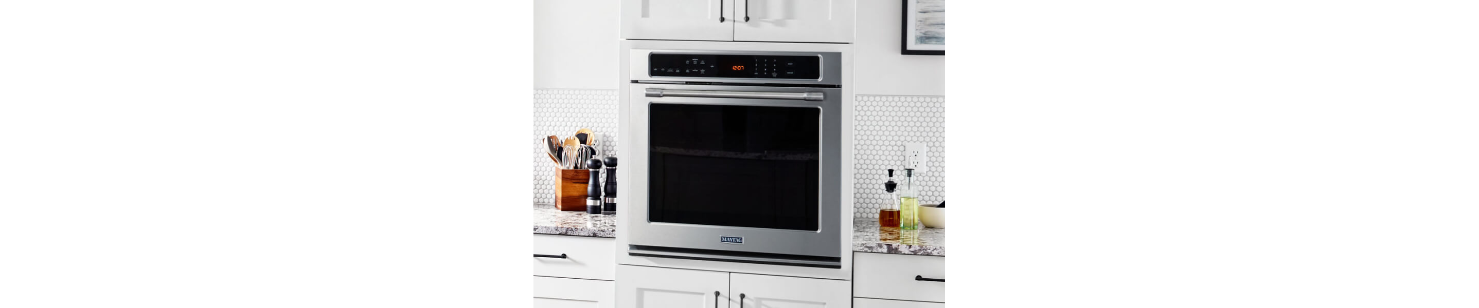 A Maytag® wall oven surrounded by white cabinetry