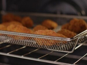 Chicken nuggets cooking in an air fry basket in the oven