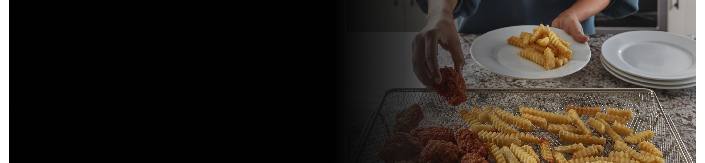 Person transferring chicken and fries from air fry basket to plate