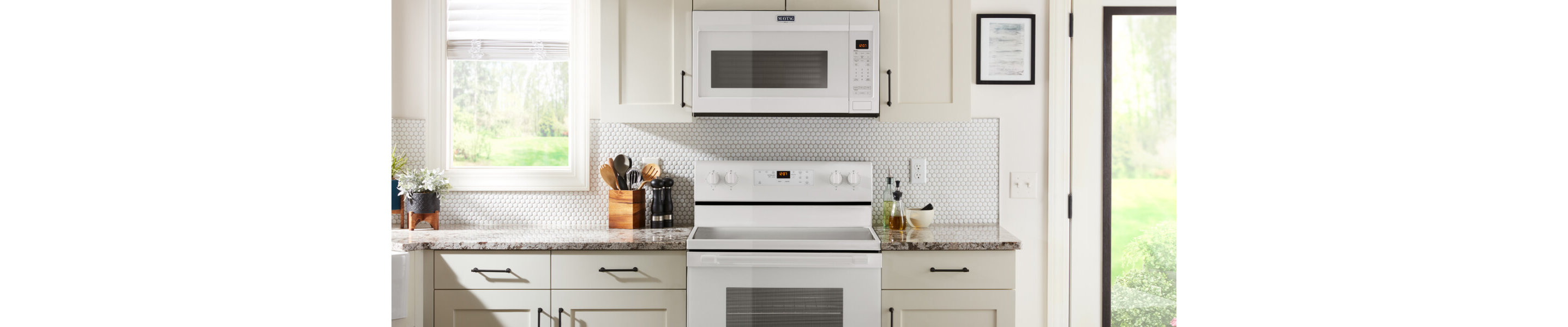 Front view of white kitchen with white Maytag® range and microwave