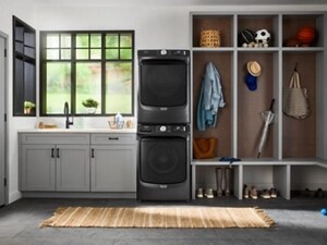 A laundry room with a stacked front load laundry pair and built-in shelving