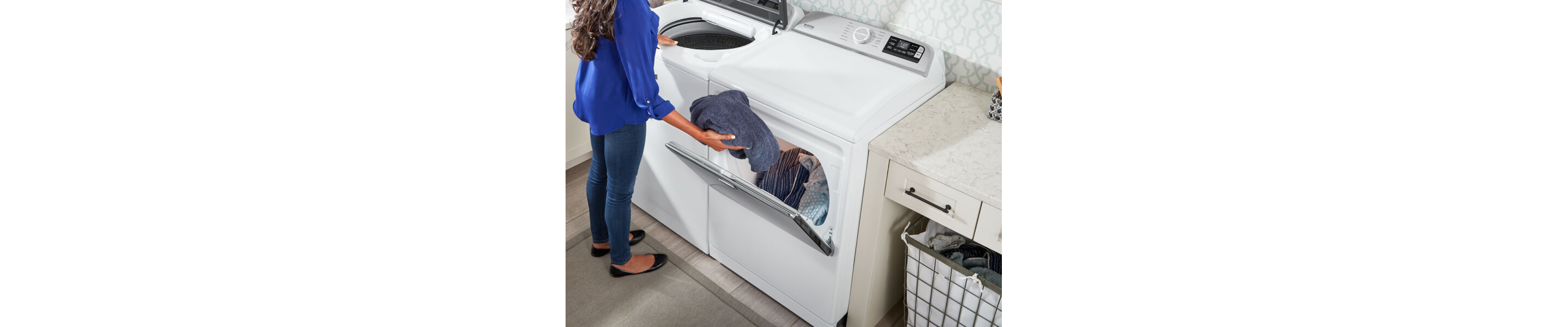 A woman placing a towel into a large capacity dryer 
