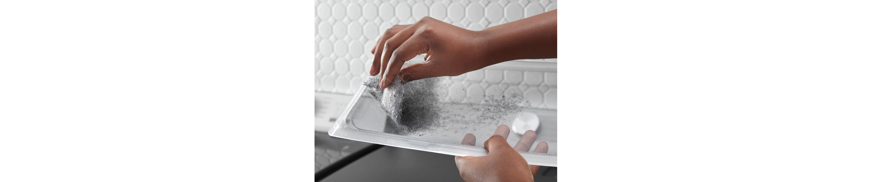 A person removing pet hair from a Maytag® dryer lint screen