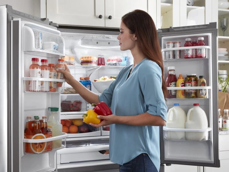 Person placing drinks in door bin of a French door refrigerator