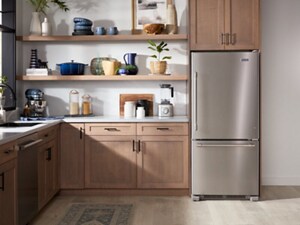 A bottom-freezer fridge surrounded by warm brown cabinetry