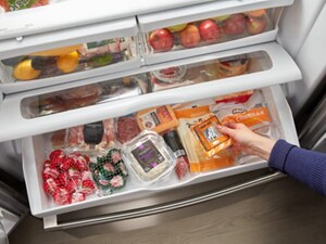 A French door fridge with a wide fridge drawer, pulled out and opened, with meat and cheese inside