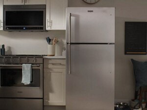 A white, top freezer refrigerator in a kitchen with white cabinetry