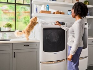 Person and cat next to a front load washer and dryer