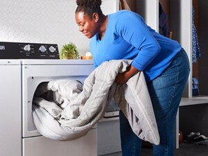 A person loading clothes into a dryer