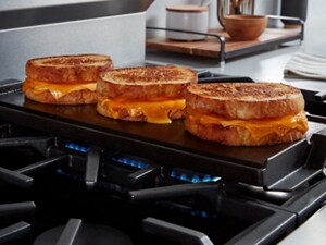 Grilled cheese on a griddle attachment on top of a gas burner