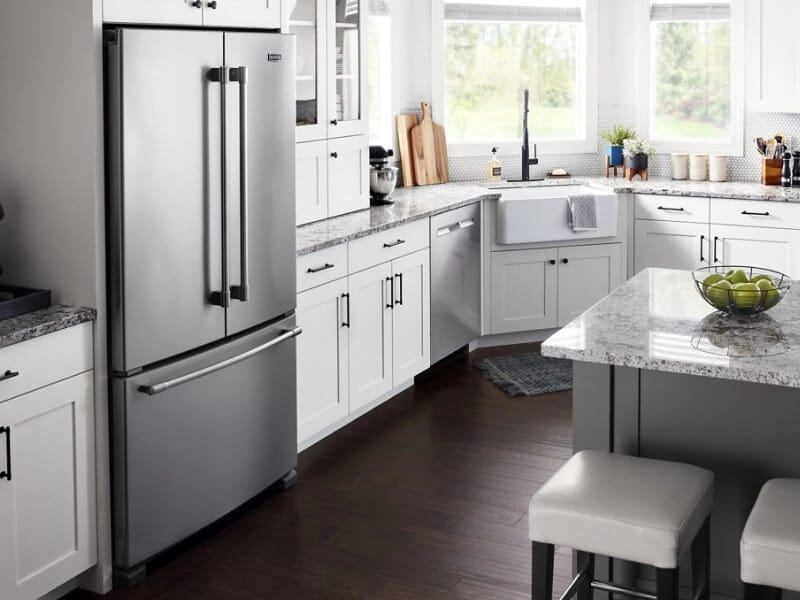 Maytag® French door refrigerator installed in white cabinetry between granite countertops