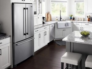 Maytag® French door refrigerator installed in white cabinetry between granite countertops