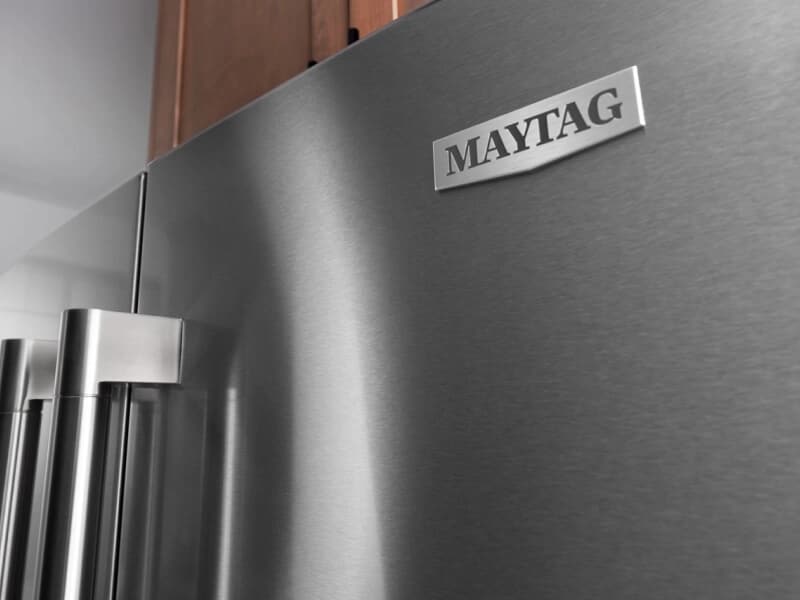 Close-up of the Maytag® badge on a stainless steel refrigerator