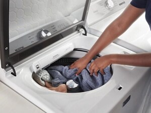 A person adding laundry to a Maytag® washer