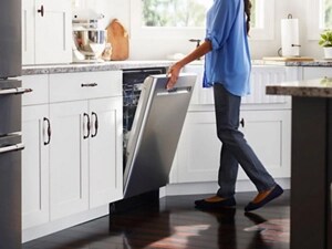 Person closing a stainless steel dishwasher