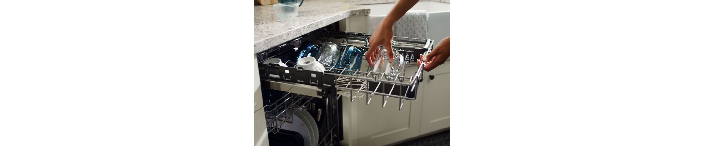 Person loading glasses on a dishwasher third rack