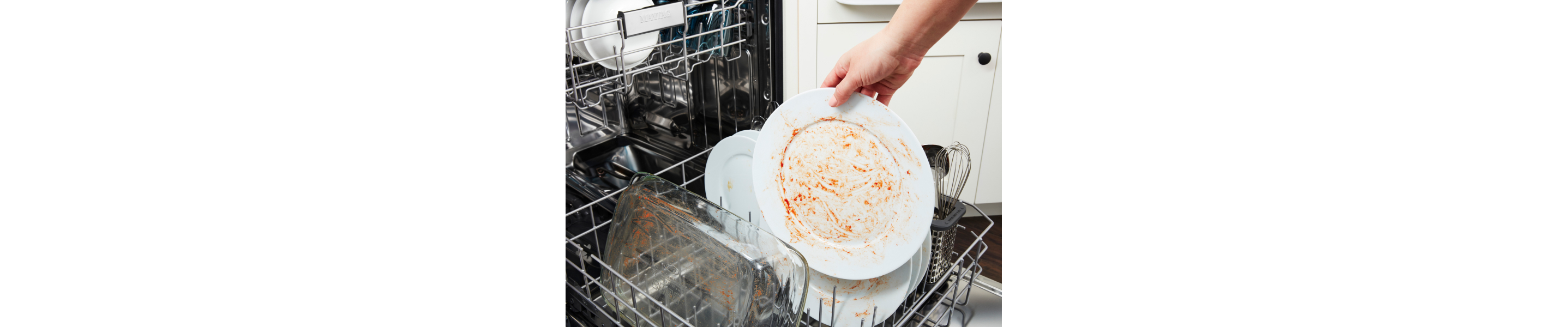 Person placing dirty dishes in a dishwasher.