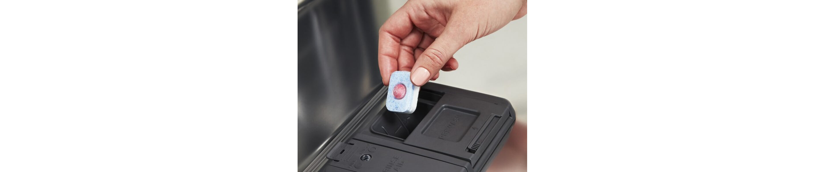Person placing tablet in dishwasher dispenser