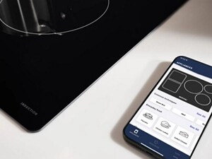 Phone with Maytag® App on counter next to cooktop