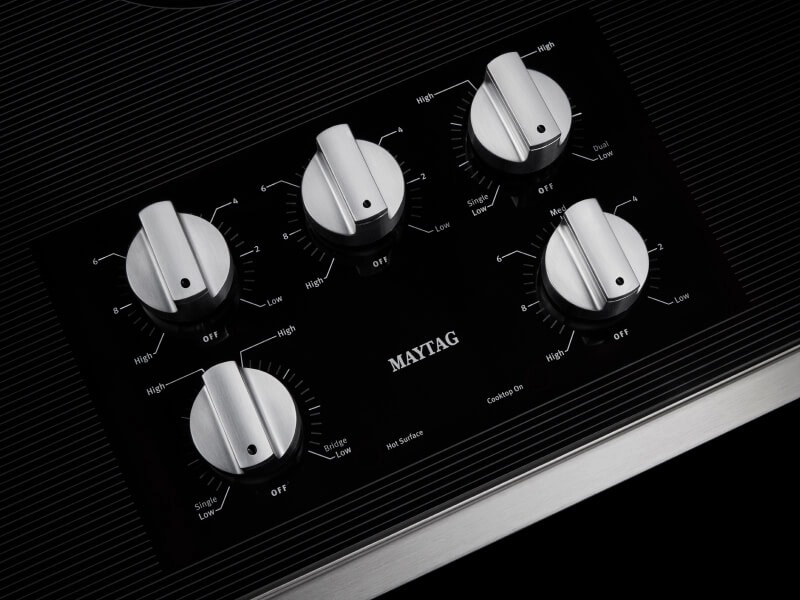 Close-up of Maytag® electric cooktop stainless steel knob controls