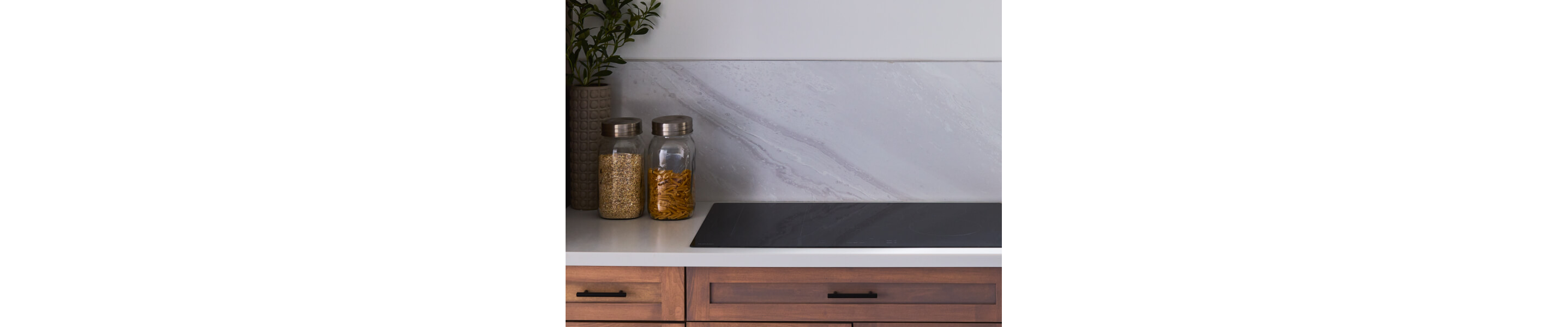 Maytag® induction cooktop in countertop next to jars of ingredients
