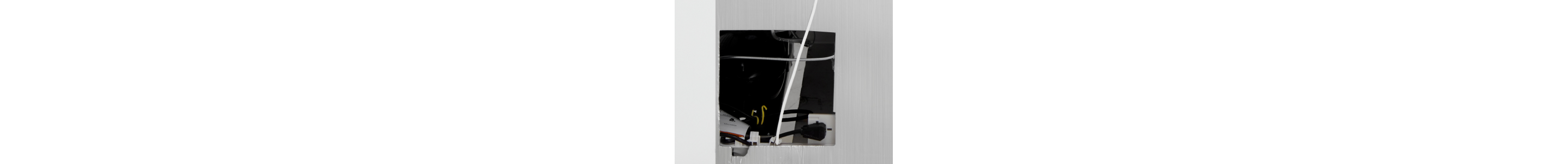 Wall cutout with power outlets and cords behind drywall