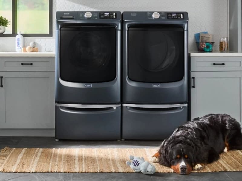 Dog laying in front of Maytag® front load washer and dryer pair