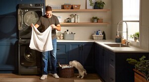 A person folding laundry next to a stackable washer and dryer