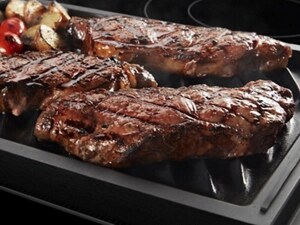 Three grilled steaks and vegetables on a grill pan