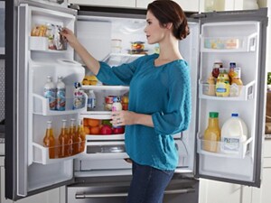 Person putting items in a refrigerator