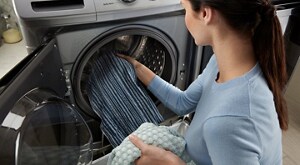 Person placing clothing inside a front load washing machine
