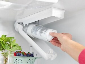 Person replacing water filter in a refrigerator