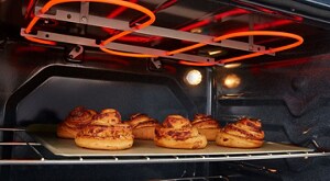 Cinnamon rolls baking under an oven heating element